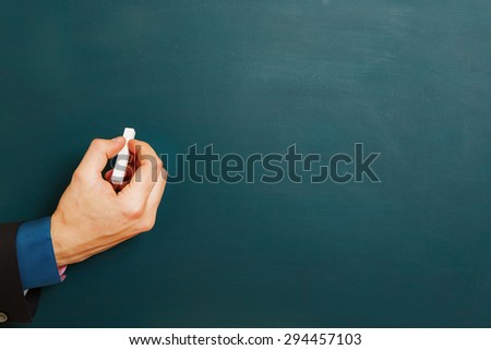 Hand of manager with white chalk on an empty chalkboard