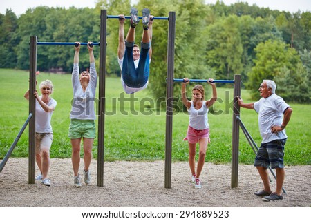 Family doing fitness training together in park at horizontal bars