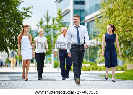 Happy group of business people walking in front of the office