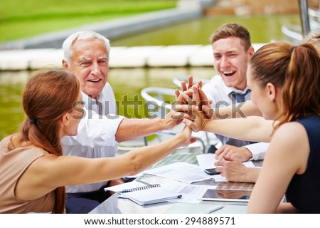 Successful business people doing high five in a meeting for motivation
