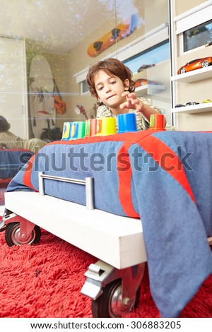 Happy boy playing in nursery in bed with his toys