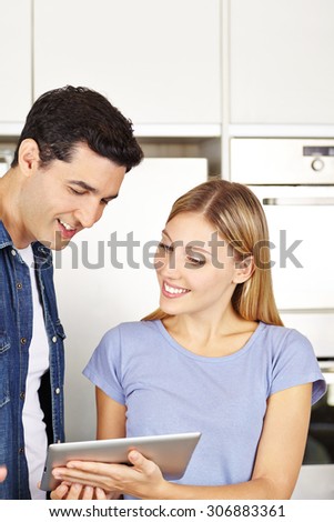 Happy couple in kitchen browsing the internet with a tablet computer