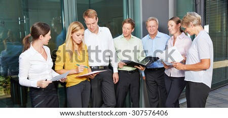 Many business people standing outside the office and talking to each other