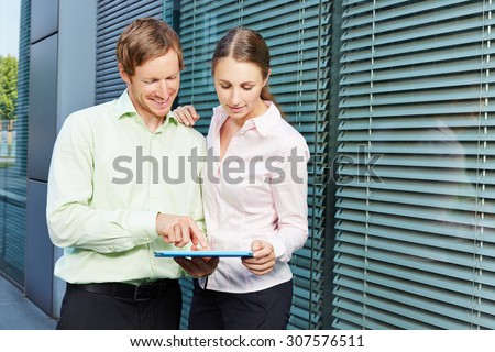 Two business people with tablet computer watching video streaming online