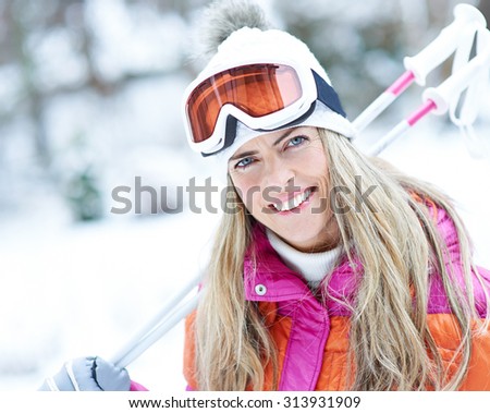 Happy skier woman smiling in winter with ski poles