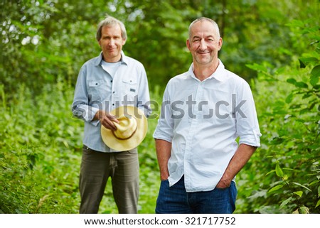 Two old men standing in summer in nature in a forest