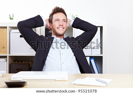 Pensive happy business man in office relaxing with hands behind his head