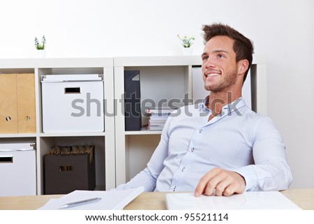 Happy business man relaxing in office at desk leaning back