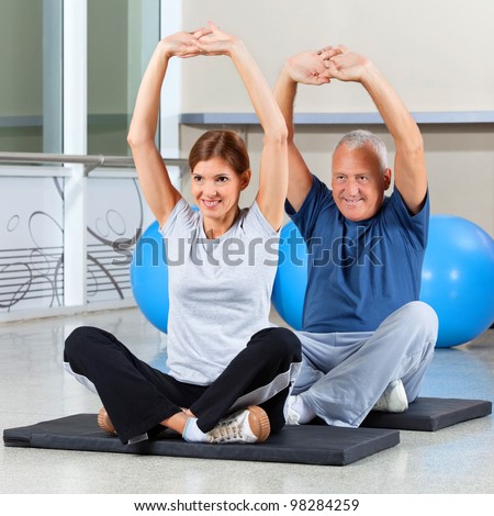 Elderly fitness group stretching their muscles on gym mats in fitness center