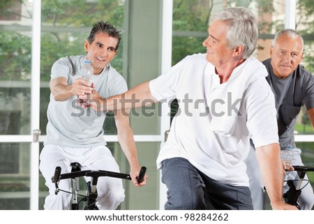 Elderly men on bikes with water in fitness center