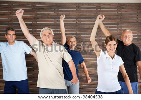 Happy senior citizens dancing to fitness music in gym