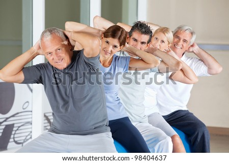 Happy senior people doing back exercises in gym