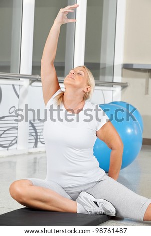 Senior woman doing breathing exercise in fitness center