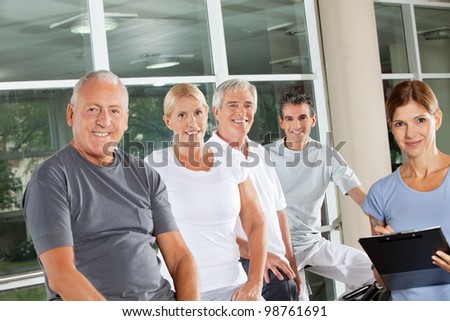 Group of happy senior people with fitness trainer in gym
