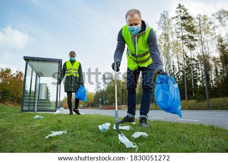 Similar – Image, Stock Photo Coronavirus garbage. Volunteers collecting used disposable medical masks and gloves near the bus stop and along the highway. The problem of environmental pollution during a pandemic COVID-19