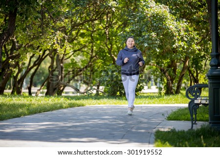 Senior woman jogging in green beautiful park. Healthy lifestyle