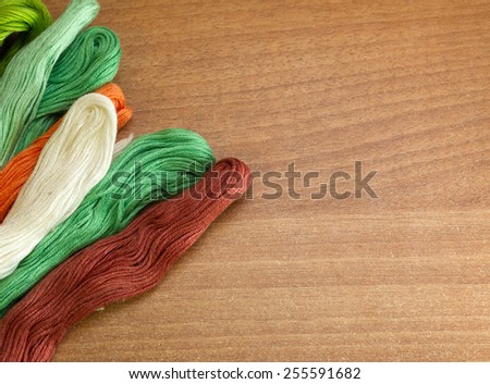 Colorful threads on a wooden background for message