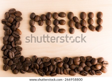 Grains of black coffee on a wooden background with word menu
