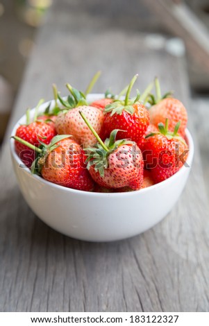 white bowl filled with strawberries on a wooden textured table t