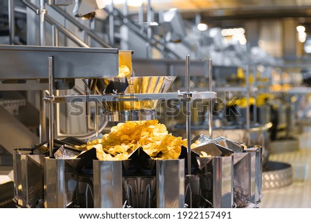 Potato chips production line at the plant. Filling machines for potato chips and snacks.
