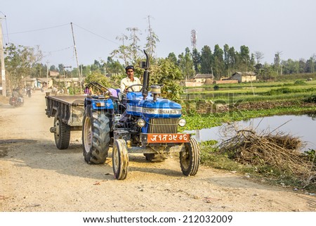 JANAKPUR, NEPAL - MARCH 18, 2014:  A modern and rich farmer in the outskirts of Janakpur Nepal, is driving his tractor along a dirt road.