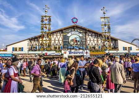 MUNICH, GERMANY - SEPTEMBER 23, 2012: Oktoberfest, Munich: One of the big beer tents. In the foreground, people are walking along, partly dressed in traditional costumes.
