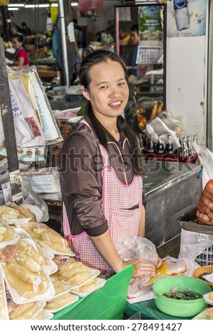 CHIANG MAI, THAILAND - JANUARY 18, 2015: market vendor at a market in Chiang Mai, Thailand, smiling at her clients.