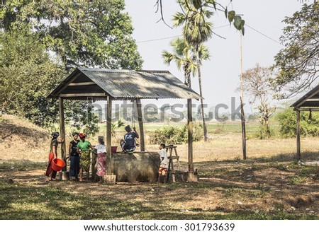 MAWLAMYINE, MYANMAR - FEBRUARY 11, 2015: Women are waiting at a rural well while the boys are pulling up the water, on the so called island of ogre at Mawlamyine, Myanmar.