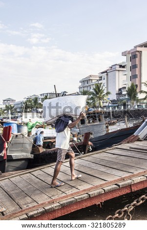 MYEIK, MYANMAR - FEBRUARY 20, 2015: A porters is carrying the cargo from the ships, that are fastened to the jetty, at Myeik in the south of Myanmar.