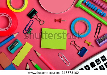 Office and school supplies on pink background