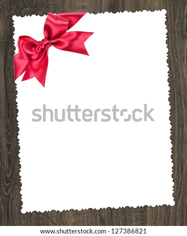 blank paper sheet with red bow on wooden background