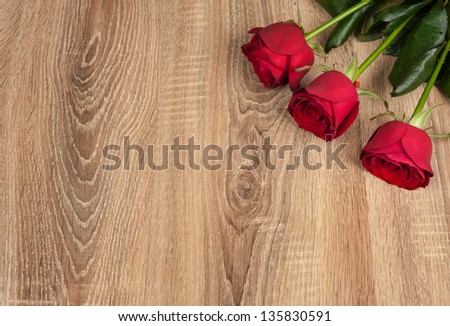 three red roses on wood