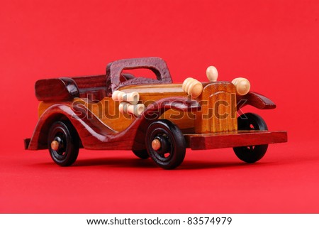 A toy car made of wood on red