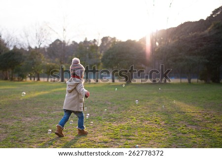 Girl to the bubble play in the park to refer the sunset