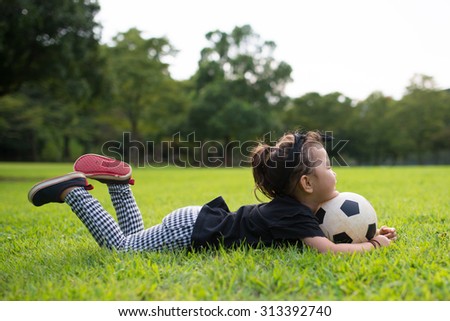 Girl lie down on the grass with a soccer ball