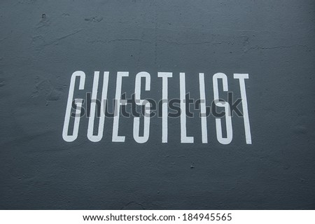 Guest list written on a black wall in white painting in front of a nightclub