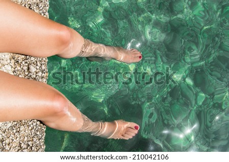Close up on legs and feet of a model bathing in a pristine Mediterranean sea in Sicily (Italy)