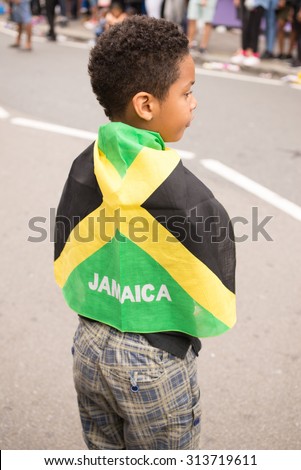 London, UK - 30 August 2015: Afro-american Boy wrapped in a Jamaica flag during the street parade for the Notting Hill Carnival, one of the biggest street festival in Europe.