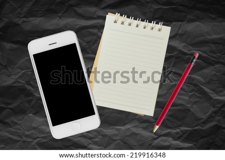 Mobile and Notebook on black paper