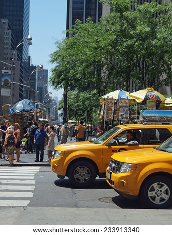 NEW YORK, NEW YORK - June 29, 2014: New York City Street Corner.  Taxis, lunch carts and people on a busy street corner in New York City.