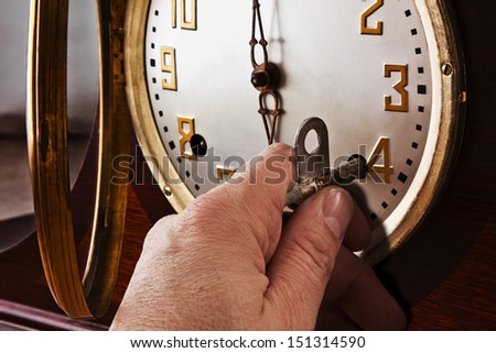 Time Winder Time winder is table top clock maintenance using a hand holding a key to wind it.