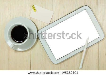 Digital tablet computer with note paper and cup of coffee on office wooden table.