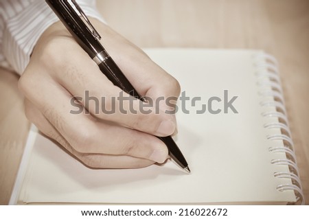 Businessman writing report on the desk in office.