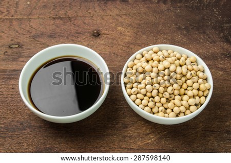 Soy sauce and soy bean in white bowl on wooden background.