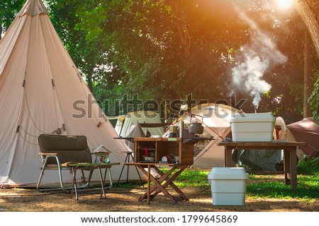 Outdoor kitchen equipment and wooden table set with field tents group in camping area at natural parkland