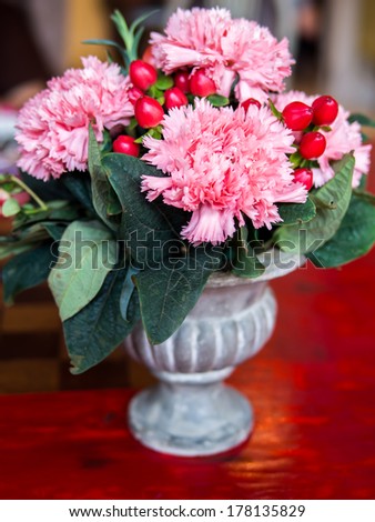 Vase of pink carnation flowers on red table top