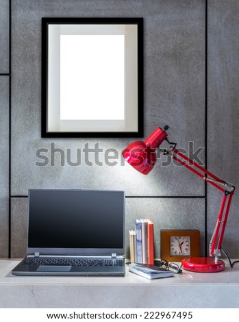 Modern office desk decorated with laptop, lamp and blank  picture frame