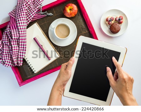 Hands using tablet computer with a wooden tray of light meal background