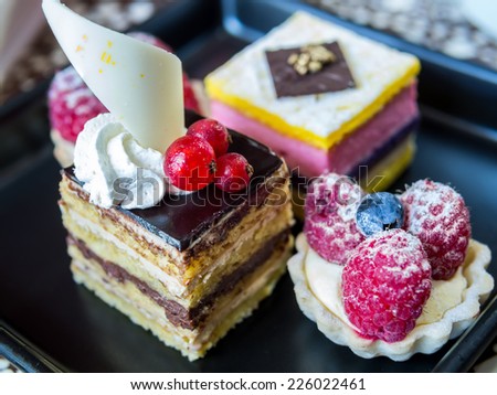 Slice of delicious  layer mousse cake and raspberries fruit tart