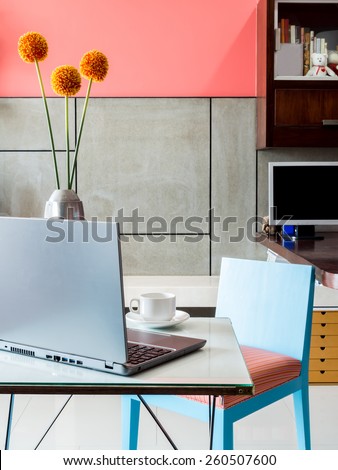 Modern workplace with laptop computer and vase of flower on desktop